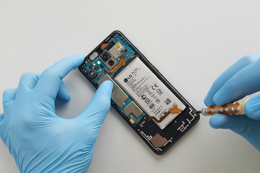 Gloved hands opening a smartphone for repair